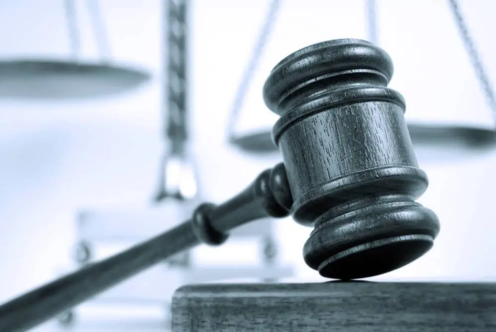 Wooden gavel resting on a desk with blurred scales of justice in the background.