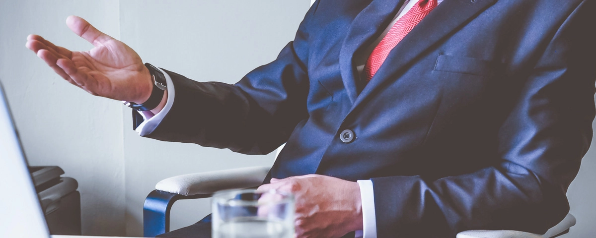 Man in business suit gesturing while speaking, representing a professional client-attorney relationship.