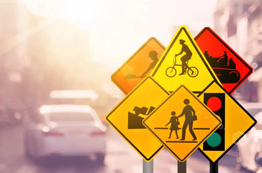 Multiple traffic signs in yellow and red, indicating construction, cyclists, pedestrians, and traffic signals.