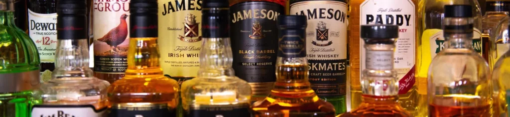 Whiskey and liquor bottles on a shelf representing underage alcohol possession and misdemeanor expungement.