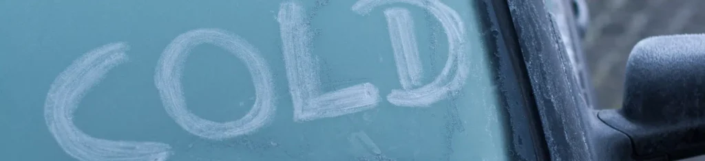 Frosted car windshield showing COLD, symbolizing winter weather effects on breathalyzer accuracy.