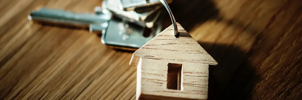 A close-up of house keys with a wooden house-shaped keychain on a table, symbolizing stability at risk due to a probation violation.