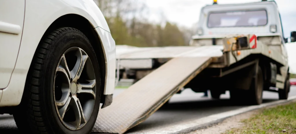 Close-up of a white car being loaded onto a tow truck, illustrating the process of vehicle seizure.