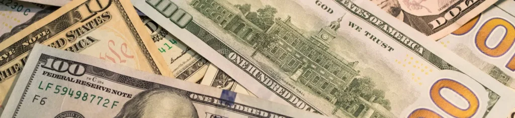 A close-up image of various U.S. dollar bills, including $100, $20, and $10 notes, illustrating financial considerations related to child support imputed income.