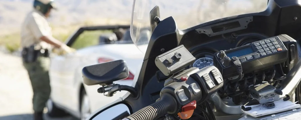 Motorcycle officer conducting a roadside traffic stop with a patrol dashboard in focus, representing evidence relevant to an NC DMV hearing.