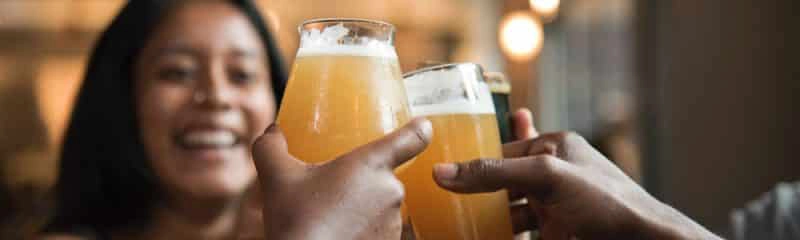 Friends clinking glasses of beer while celebrating, highlighting the importance of staying safe Thanksgiving Eve.