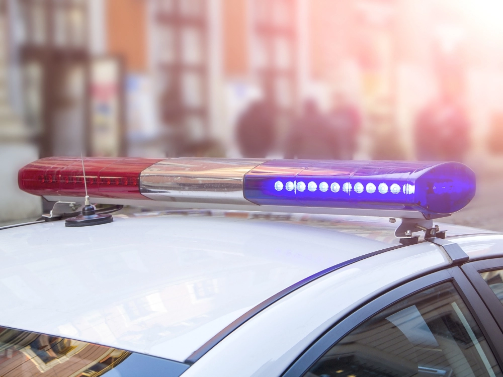 Police car emergency lights flashing in city at night.