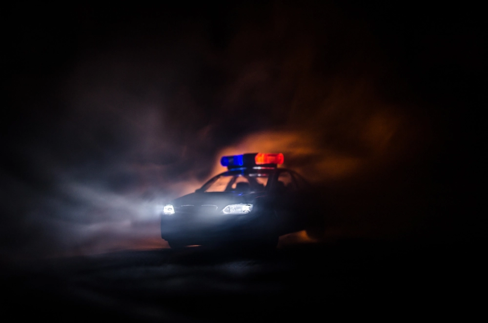 Police car model with red and blue flashing lights in dark smoky background.
