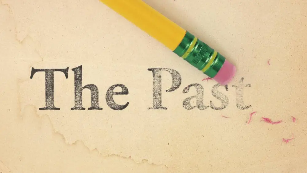 Eraser partially removing the text "The Past" from a textured, yellowed paper background.