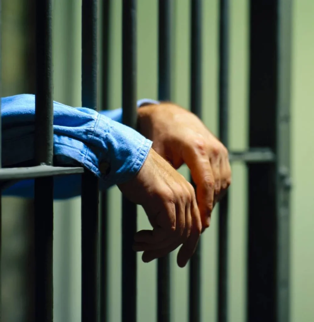 Prison cell interior with metal bars and dim lighting.
