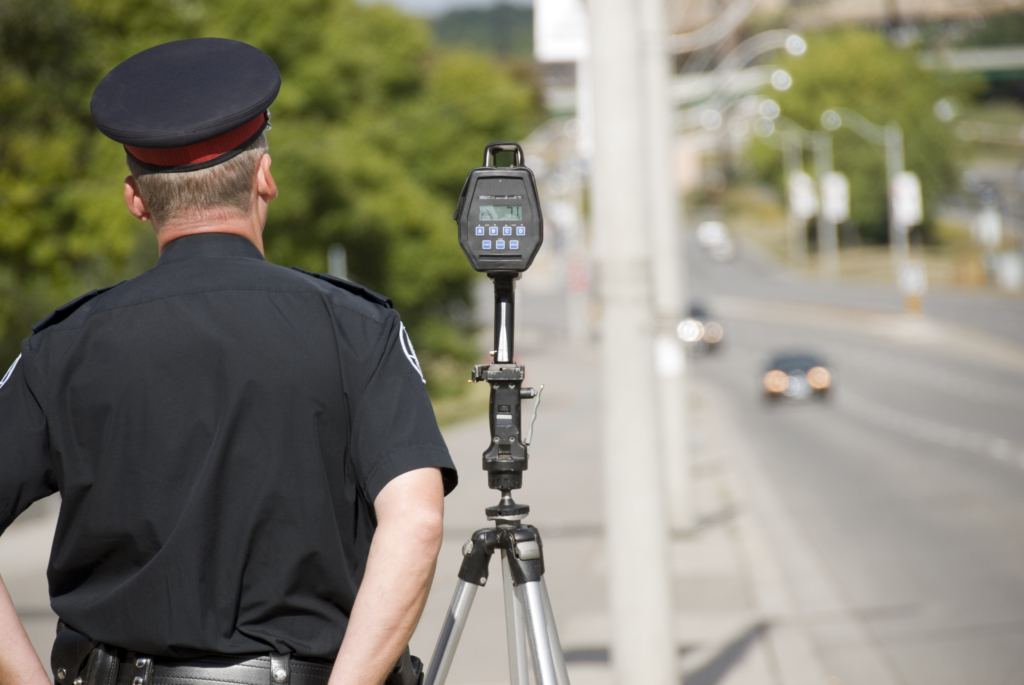 Driver receiving speeding ticket from police officer on city street.